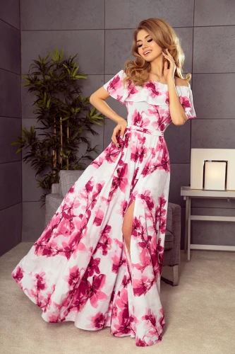 Eine elegante, lange Kleid mit spanischem Ausschnitt und lebhaftem Blumenmuster in Rosa- und Weißtönen. Der fließende Stoff und der seitliche Schlitz verleihen dem Kleid eine feminine und stilvolle Note.}
