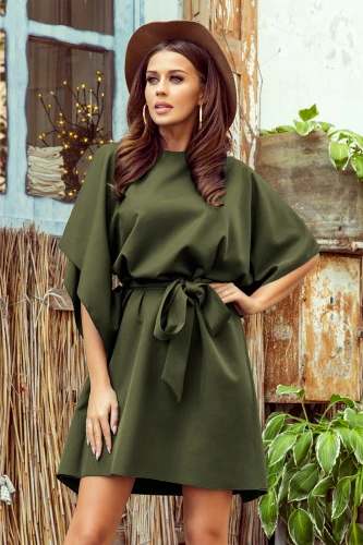 Eine elegante, olivgrüne Kleid mit weiten Ärmeln und einem passenden Gürtel, der die Taille betont. Perfekt für einen stilvollen, lässigen Look, kombiniert mit einem Hut und dezentem Schmuck.}