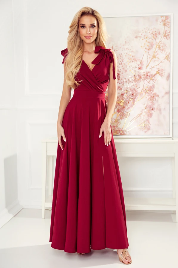 Langes, elegantes Kleid in tiefem Rot mit V-Ausschnitt und Schleifendetails an den Schultern. Der fließende Stoff und die schmeichelhafte Passform verleihen dem Kleid eine zeitlose Eleganz.