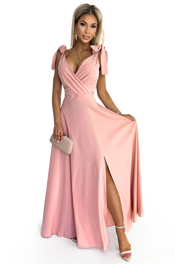 Elegantes, langes Kleid in zartem Rosa mit tiefem V-Ausschnitt und Schleifendetails an den Schultern. Der fließende Rock hat einen hohen Schlitz, der für einen femininen und stilvollen Look sorgt.