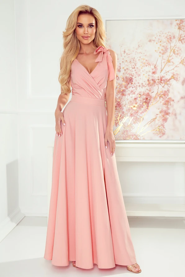 Langes, elegantes Kleid in zartem Rosa mit einem Wickeloberteil und einer Schleife an der Schulter. Der fließende Rock verleiht dem Kleid eine anmutige Silhouette.
