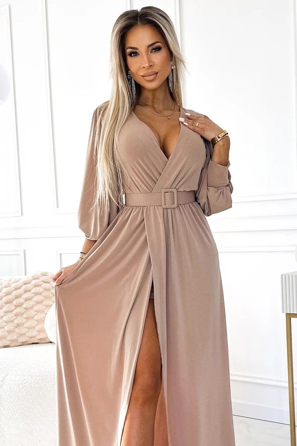 Elegantes, langes Kleid in Beige mit tiefem V-Ausschnitt und Gürtel, das eine feminine Silhouette betont. Der fließende Stoff und der seitliche Schlitz verleihen dem Kleid eine stilvolle und moderne Note.