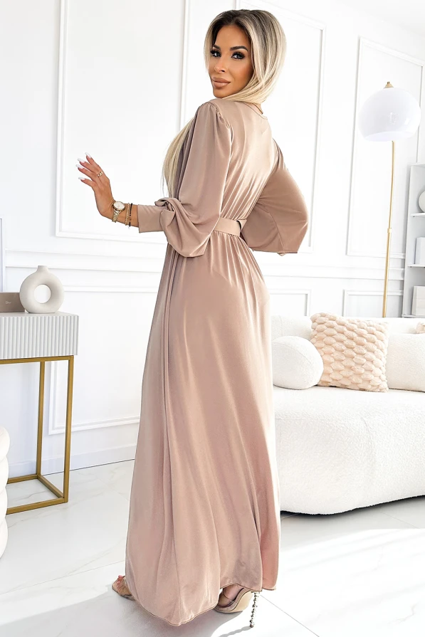Eine elegante, lange Damenkleid in sanftem Beige mit fließendem Stoff und Gürtel, ideal für besondere Anlässe. Die weiten Ärmel und der dezente Glanz verleihen dem Kleid eine stilvolle und zeitlose Ausstrahlung.