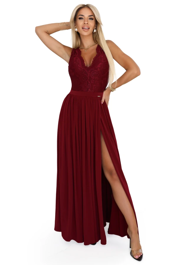Modelka prezentuje długą bordową suknię LEA marki Numoco z koronkową górą, odkrytymi plecami i wysokim rozcięciem na nodze, idealną na eleganckie uroczystości.