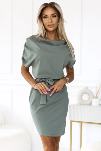 Eine elegante, asymmetrische Damenkleid in einem sanften Olivgrün, das durch einen stilvollen Gürtel in der Taille akzentuiert wird. Der fließende Stoff und der moderne Schnitt verleihen dem Kleid eine zeitlose Eleganz.}