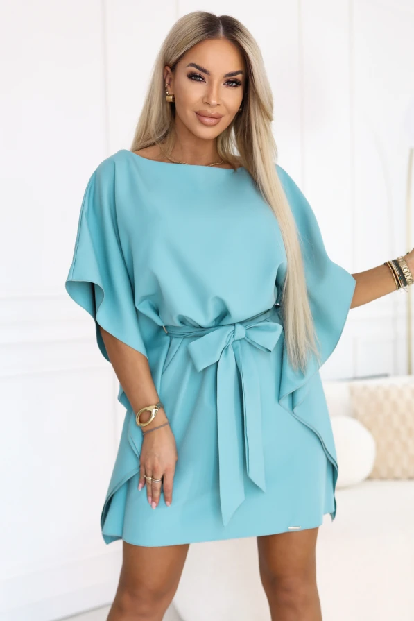 Model im türkisfarbenen Numoco-Minikleid mit Fledermausärmeln und einem in der Taille gebundenen Gürtel.