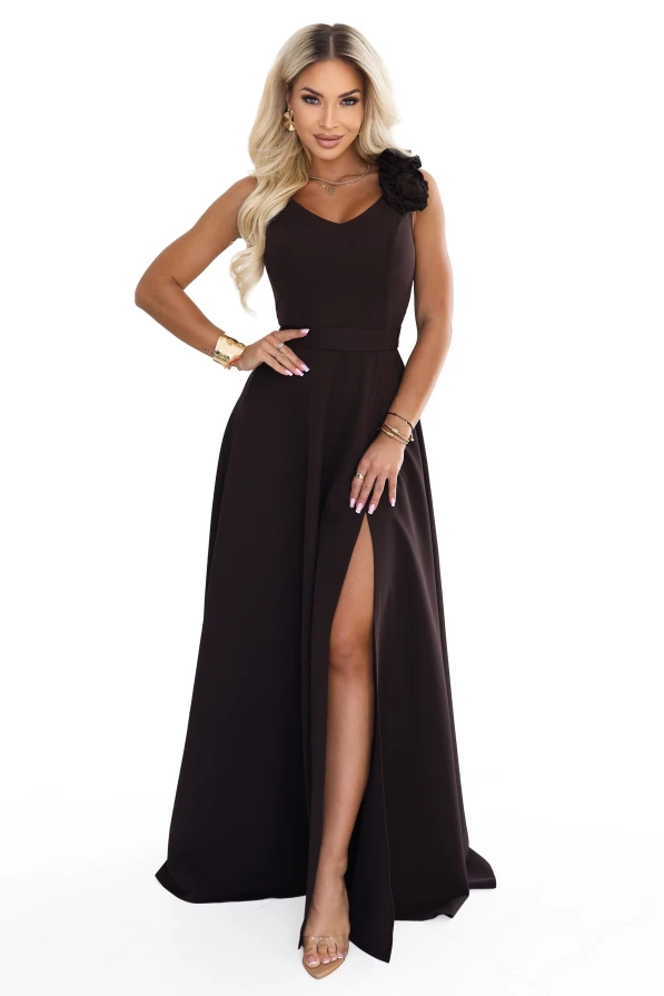 Das Model trägt ein elegantes schokoladenbraunes Maxikleid mit herzförmigem Ausschnitt, Beinschlitz und einer dekorativen Blume an der Schulter.