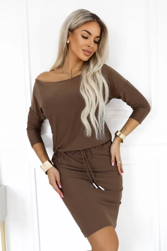 Model in einem sportlichen Numoco Kleid in Mokkabraun mit Bootausschnitt, der eine Schulter freilässt, 3/4-Ärmeln, Taschen und Bindung in der Taille.}