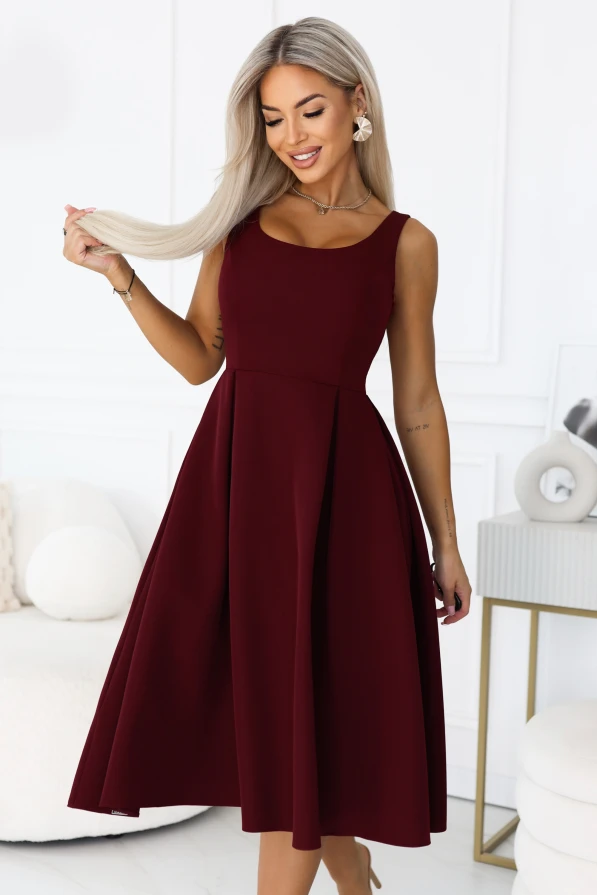 Model im bordeauxfarbenen Midikleid ALVA von Numoco mit breiten Trägern, rundem Ausschnitt, betonter Taille und ausgestelltem Rockteil mit Falten.