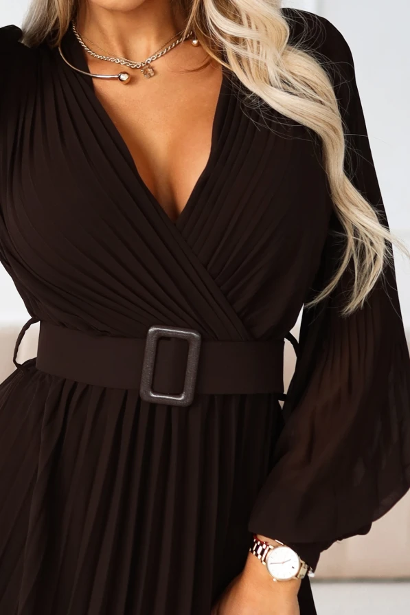 Modelka w brązowej sukience maxi z paskiem i kopertowym dekoltem, prezentująca zwiewny, plisowany dół idealny na wieczorne wyjścia.