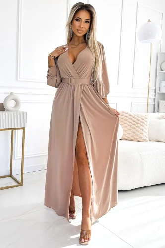 Elegantes, langes Kleid in sanftem Beige mit tiefem V-Ausschnitt und einem stilvollen Gürtel, der die Taille betont. Der fließende Stoff und der hohe Schlitz verleihen dem Kleid eine verführerische Note.}
