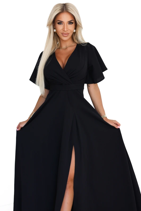 Modelka w eleganckiej czarnej sukni maxi z kopertowym dekoltem i rozcięciem na nodze, prezentująca wieczorową stylizację od polskiego producenta sukienek Numoco.