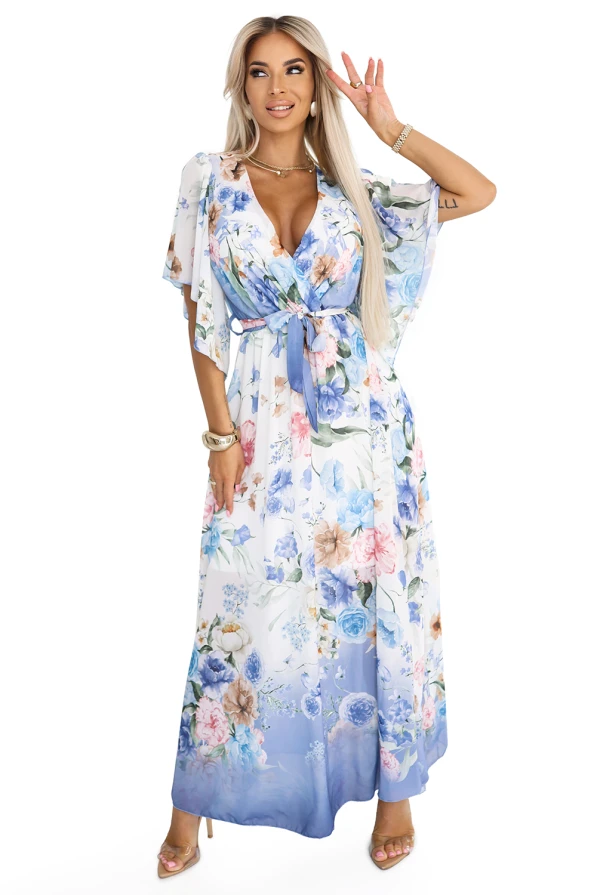 Modelka prezentuje romantyczną, kwiatową sukienkę maxi z przewiewnego szyfonu, ozdobioną pastelowym wzorem w odcieniach niebieskiego. Stylizacja podkreśla kobiecą sylwetkę i idealnie wpisuje się w letni klimat eleganckich przyjęć i spacerów.