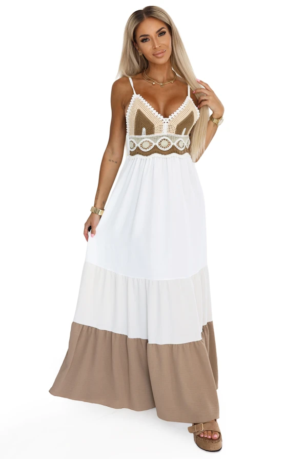 Modelka prezentuje letnią sukienkę maxi na ramiączkach w stylu boho od Numoco Basic – z ażurowym brązowo-kremowym topem i rozkloszowanym dołem w odcieniach bieli i beżu. Idealna stylizacja na wakacje, plażę lub letni spacer.