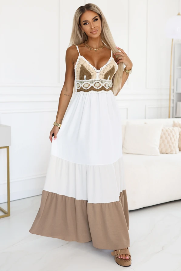 Modelka prezentuje letnią sukienkę maxi na ramiączkach w stylu boho od Numoco Basic – z ażurowym brązowo-kremowym topem i rozkloszowanym dołem w odcieniach bieli i beżu. Idealna stylizacja na wakacje, plażę lub letni spacer.