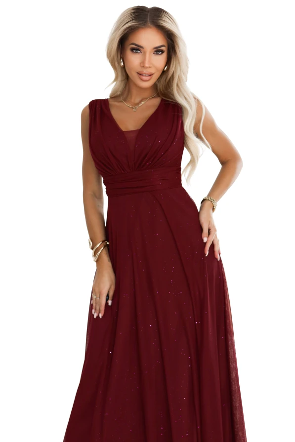 Modelka prezentuje długą bordową sukienkę wieczorową Numoco Basic z dekoltem V i subtelnym brokatowym połyskiem