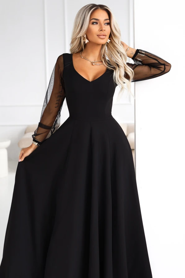 Modelka prezentuje czarną wieczorową suknię Numoco z dekoltem V i półprzezroczystymi rękawami.