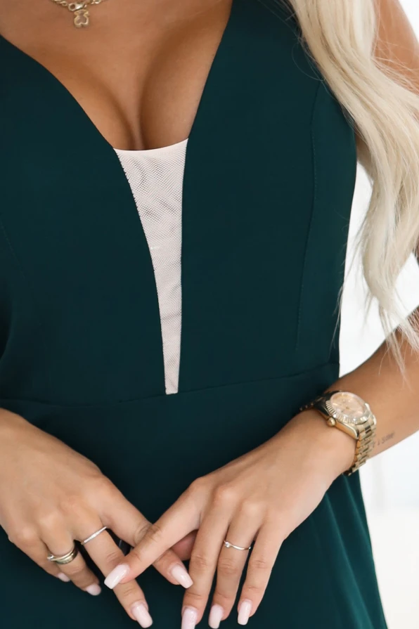 Modelka prezentuje elegancką długą suknię wieczorową w kolorze butelkowej zieleni z głębokim dekoltem i wysokim rozcięciem na nodze, polska marka Numoco.