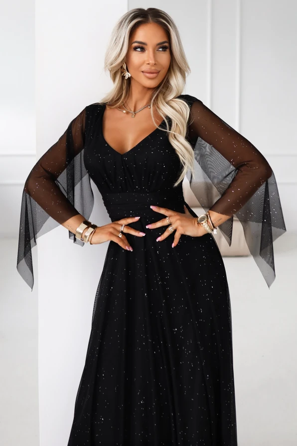 Elegancka czarna sukienka maxi z błyszczącymi detalami i tiulowymi rękawami na bal, stylizowana w luksusowym wnętrzu glamour.